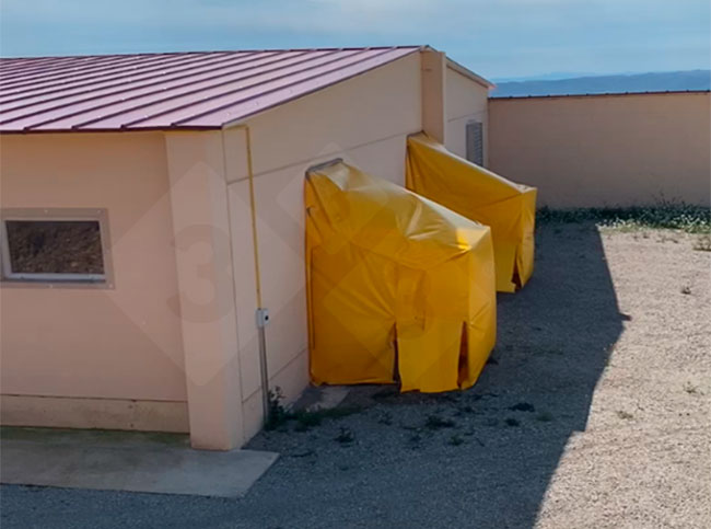 Photo 2. Sur les ventilateurs d'extraction d'air du b&acirc;timent N2, un d&eacute;flecteur en plastique a &eacute;t&eacute; install&eacute; afin de diriger l'air sortant vers le sol, o&ugrave; ont &eacute;t&eacute; dispos&eacute;s de grands bacs contenant un d&eacute;sinfectant virucide.
